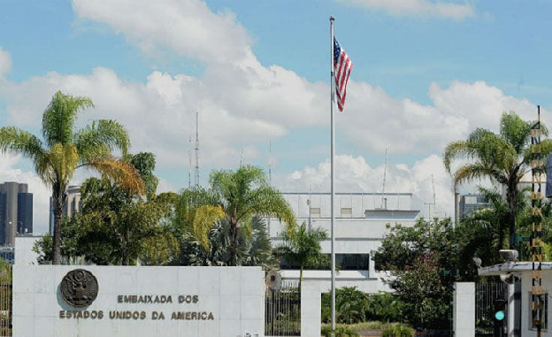 Fachada da Embaixada dos Estados Unidos da América com bandeira americana ao vento e palmeiras ao redor
 Fachada da Embaixada dos Estados Unidos da América com bandeira americana ao vento e palmeiras ao redor