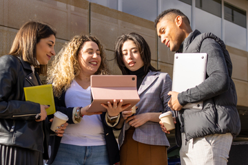Grupo de jovens profissionais colaborando e discutindo ideias com um tablet ao ar livre
